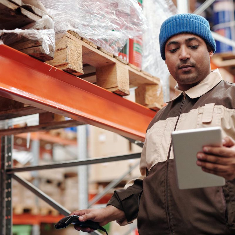 Un préparateur entrain de scanner un produit et de regarder sa tablette.