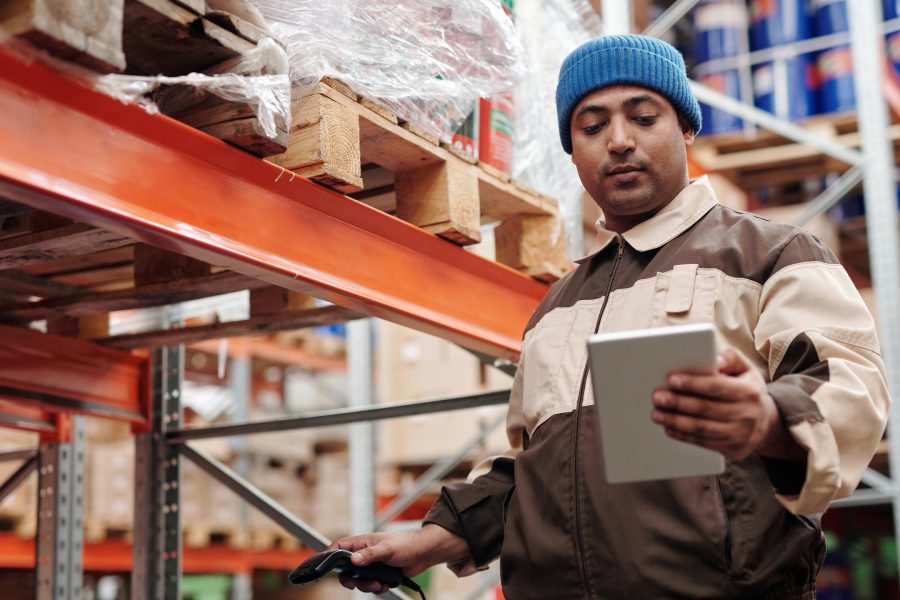 Un préparateur entrain de scanner un produit et de regarder sa tablette.